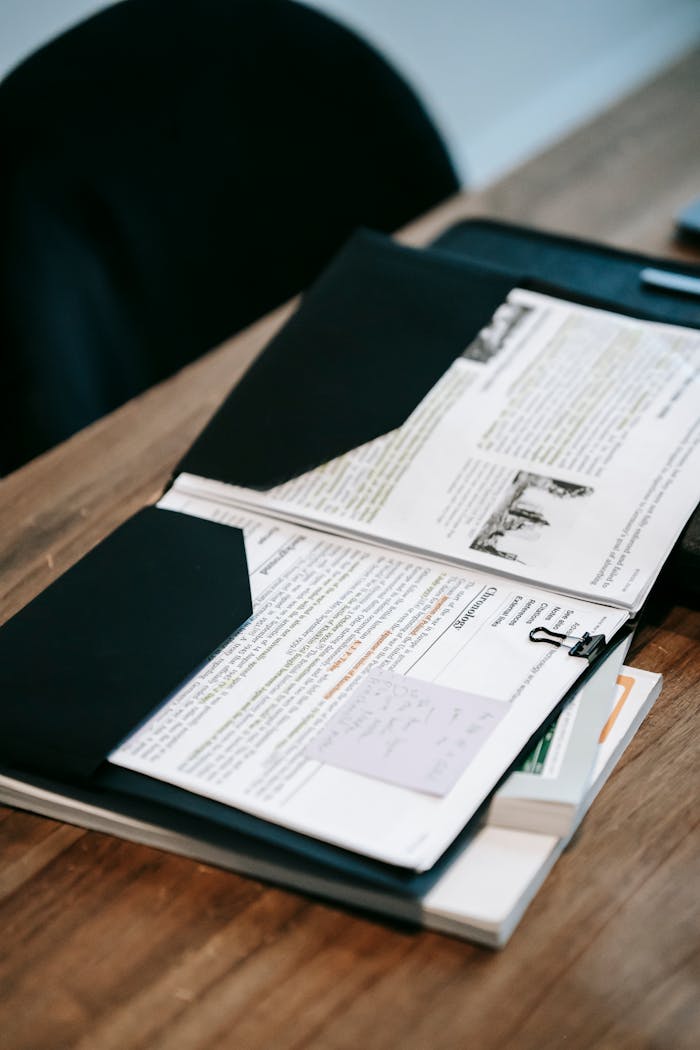 services-04 An open folder with papers and documents on a wooden desk representing educational or business material.