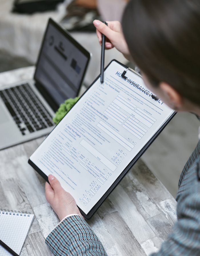 Mastering the First Impression: Your intriguing post title goes here An adult reviews a home insurance policy document at a desk with a pen and laptop.